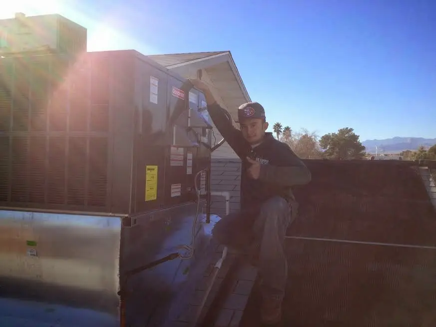 HVAC technician performing Air Duct Cleaning on a rooftop unit in Boulder City